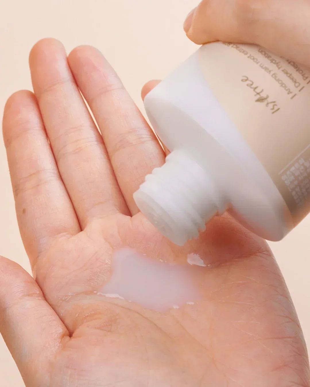 Close-up of hand pouring milky toner from 151three vegan skincare bottle