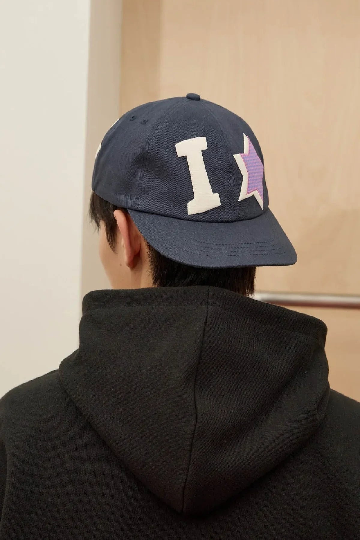 Navy ball cap with cream I and purple star appliqué, Korean fashion style, worn with black hoodie.