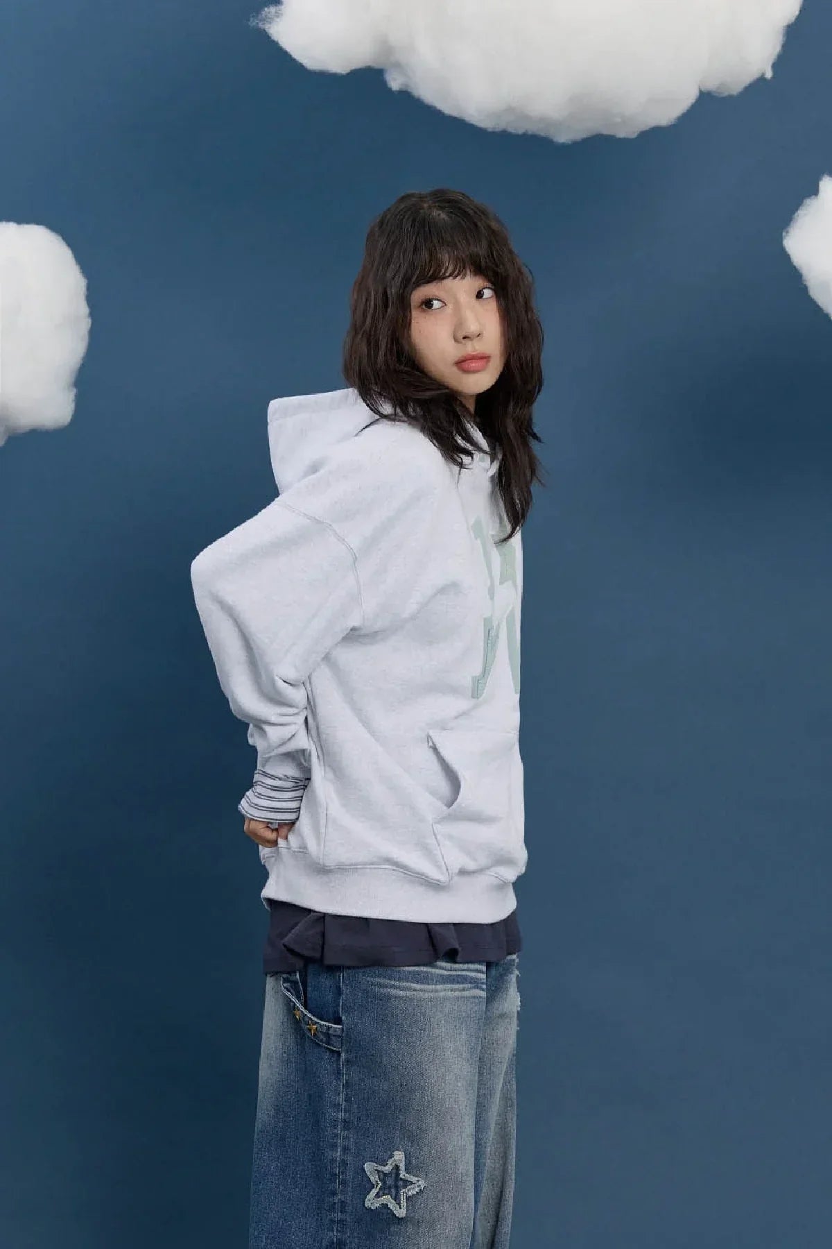 Model in a light grey hoodie and star-patch denim jeans, styled for Korean fashion on Malkn