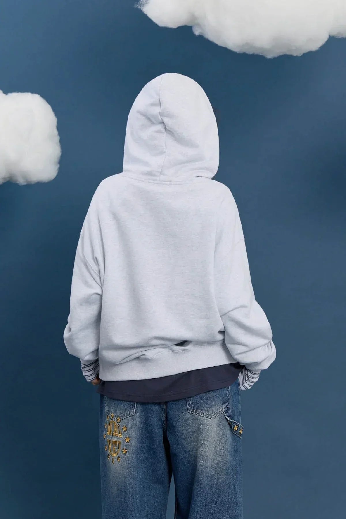 Back view of model in melange white hoodie and embroidered blue jeans, Korean fashion style