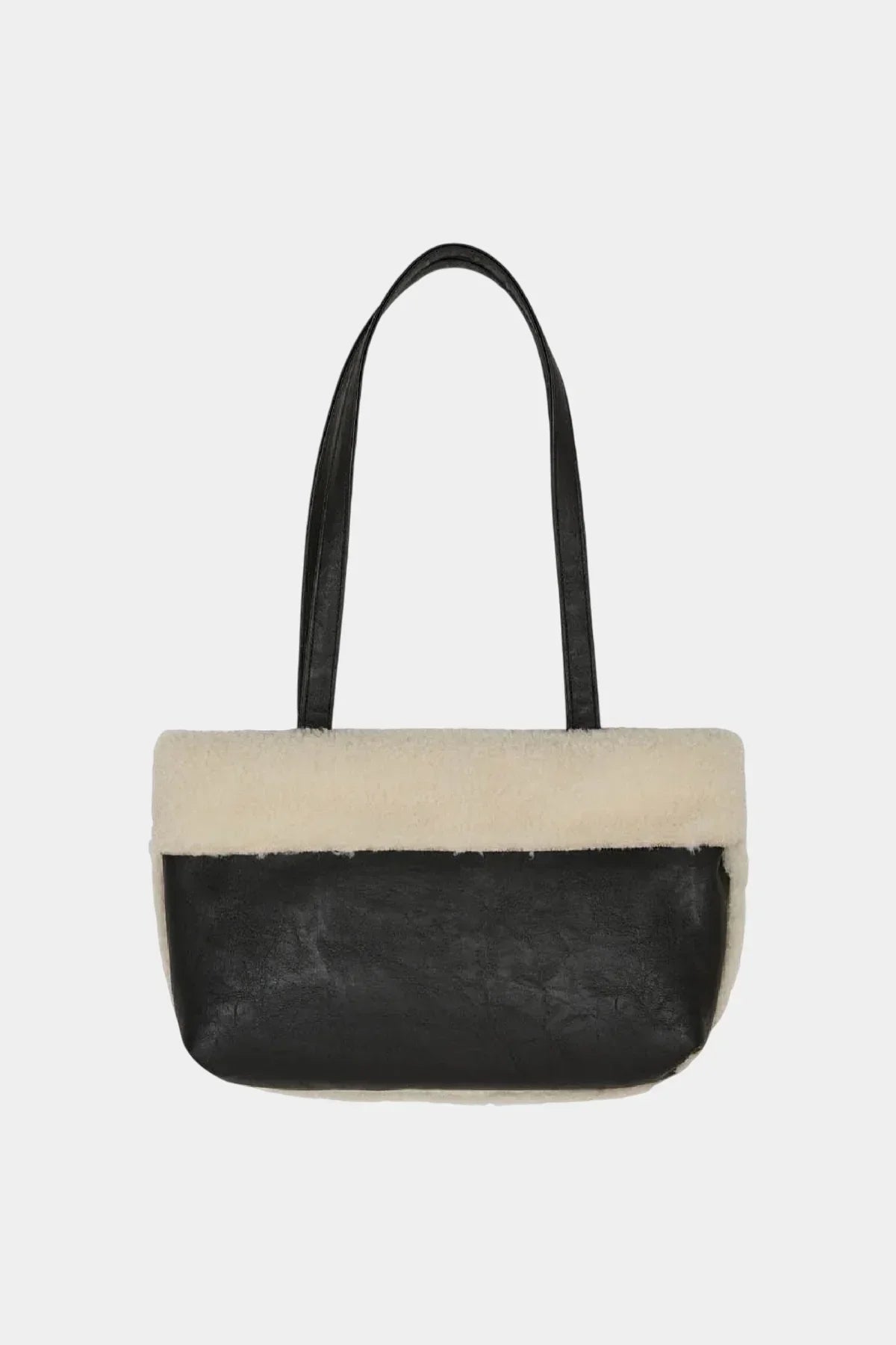 Black leather shoulder bag with cream shearling trim and long straps on white background