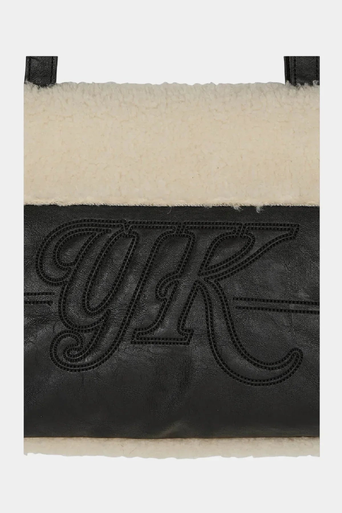 Black leather detail with stitched 'YK' lettering on a cream shearling shoulder bag