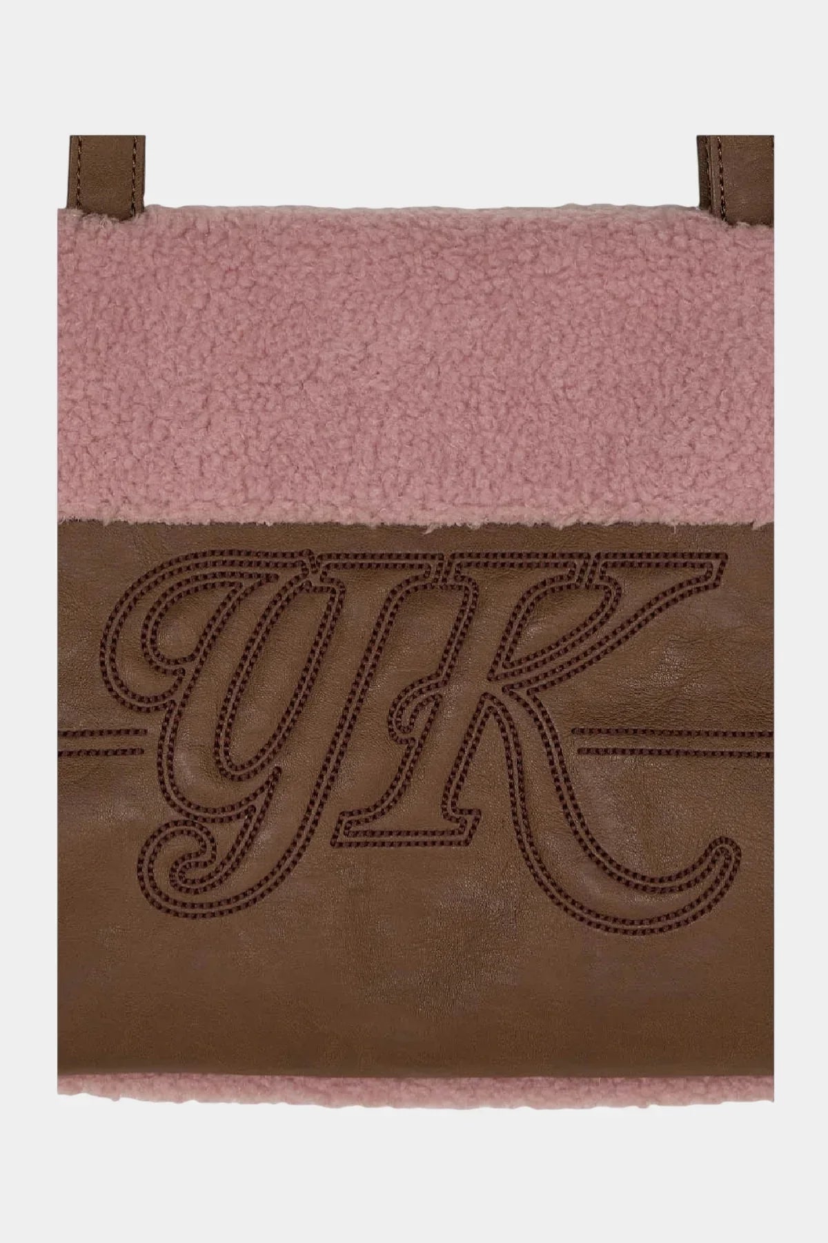 Close-up of brown leather patch with embroidered YK logo on pink fleece fabric shoulder bag
