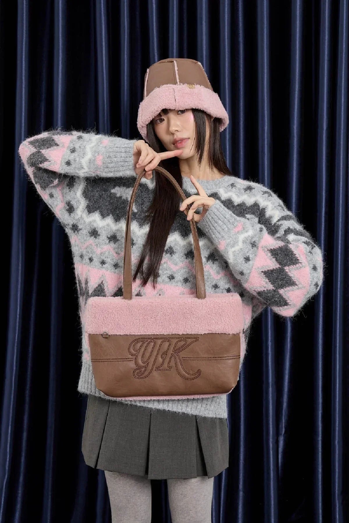 Woman in patterned sweater and bucket hat holding a brown and pink YK leather shoulder bag