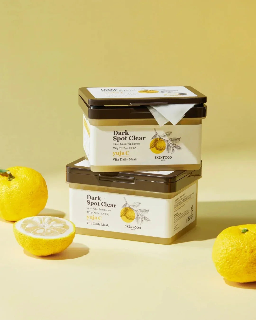 Skinfood Yuja C Dark Spot Clear Vita Daily Mask containers with fresh yuja citrus on yellow background