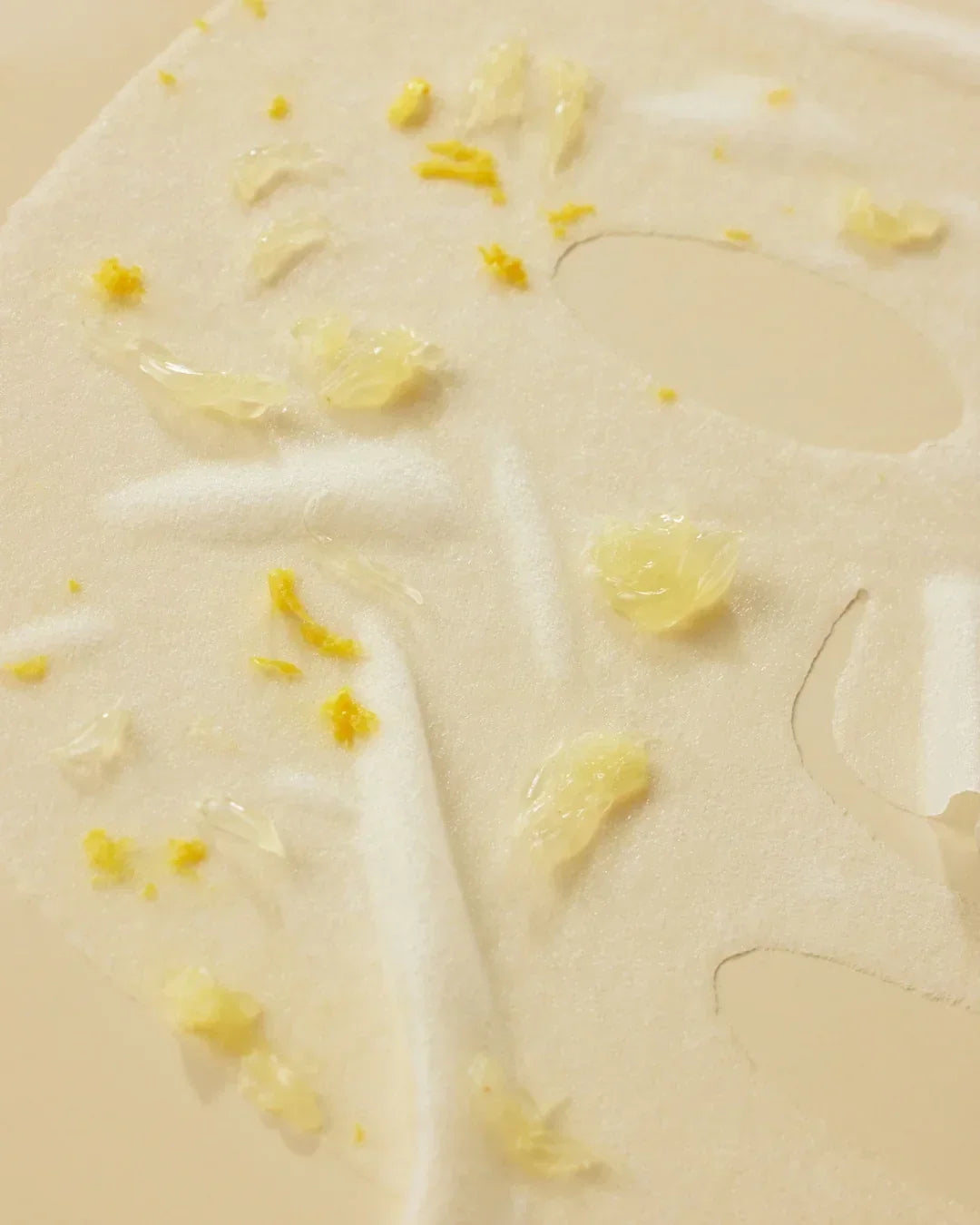 close-up of textured sheet mask with niacin serum and yellow flower petals for skincare