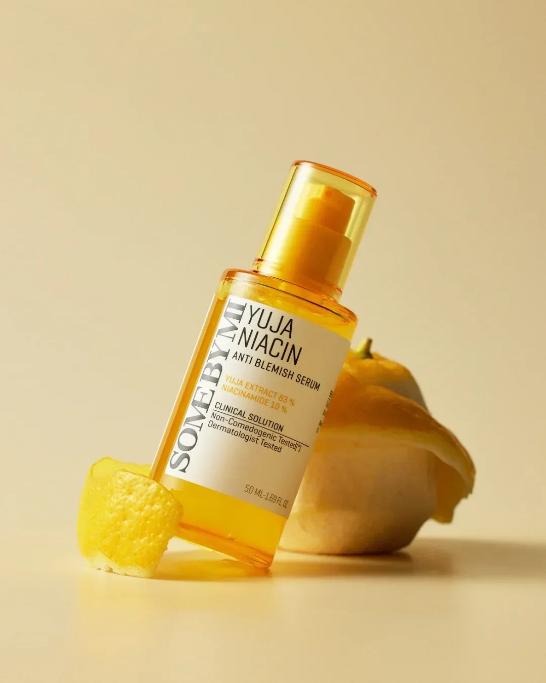 Yuja Niacin Anti Blemish Serum bottle with yellow citrus peel on beige background