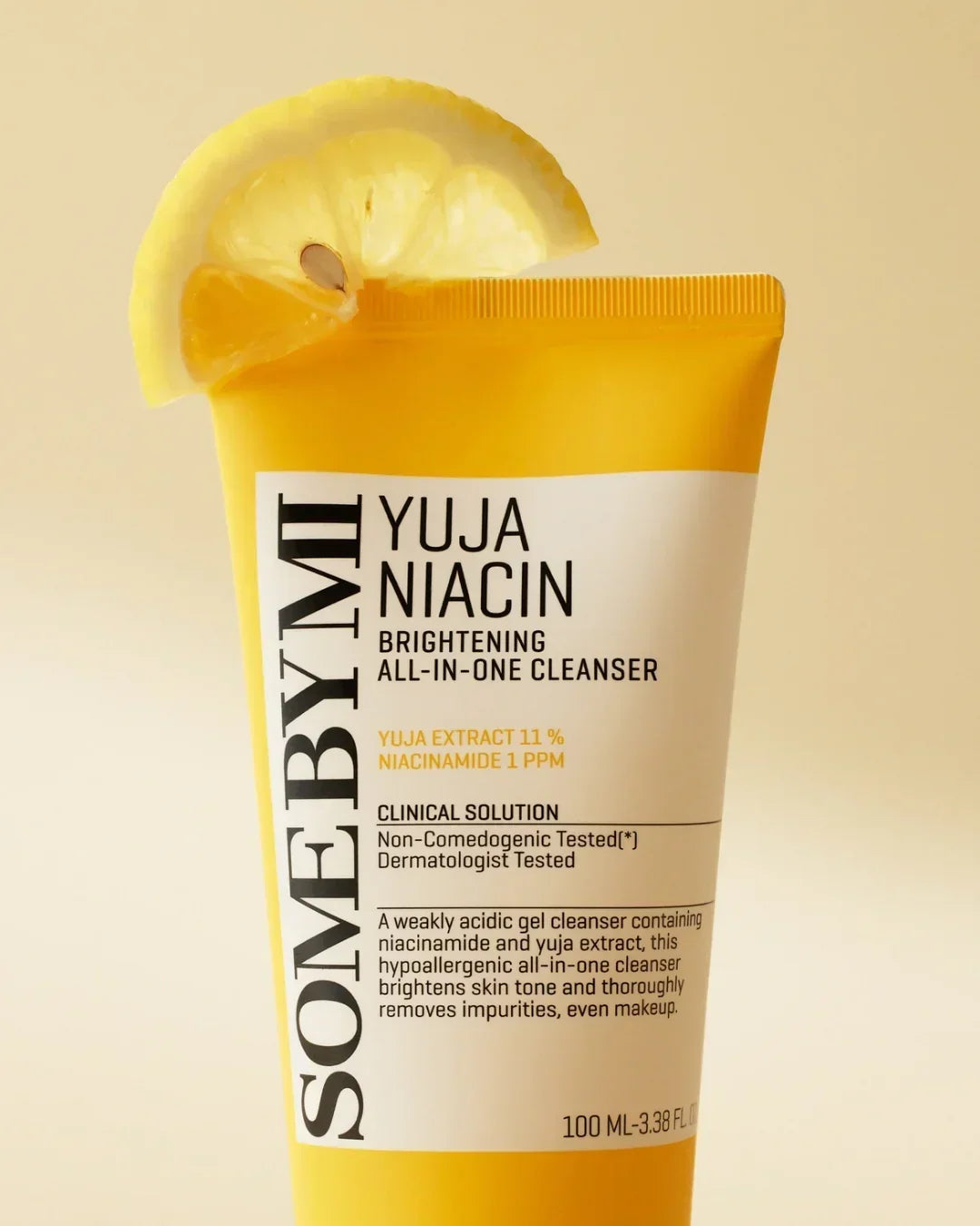 SOMEBYMI Yuja Niacin Brightening All-In-One Cleanser tube with lemon slice on yellow background
