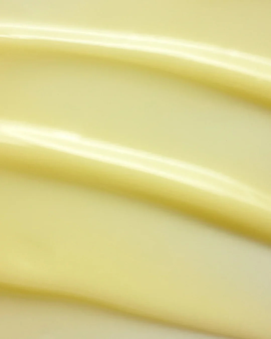 Smooth creamy yellow moisturizer texture swatched in soft light