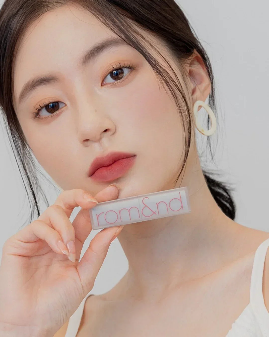 Close-up of woman with soft matte lipstick holding rom&nd lipstick in hand