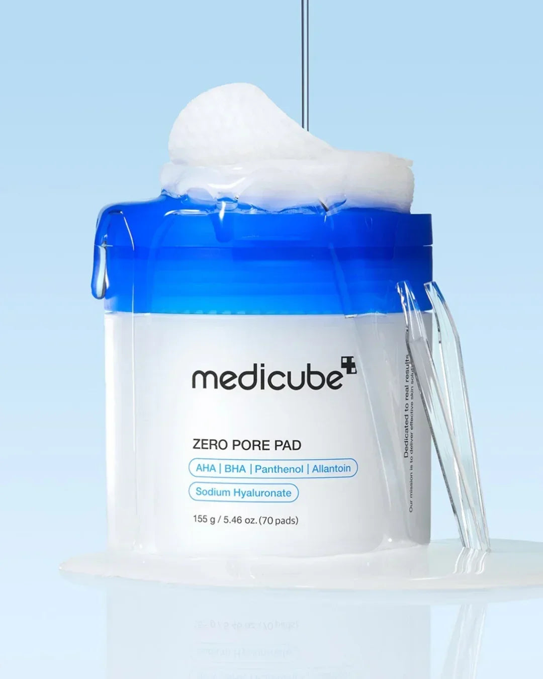 Medicube Zero Pore Pad container with blue lid, white cotton pads, and clear liquid on reflective surface