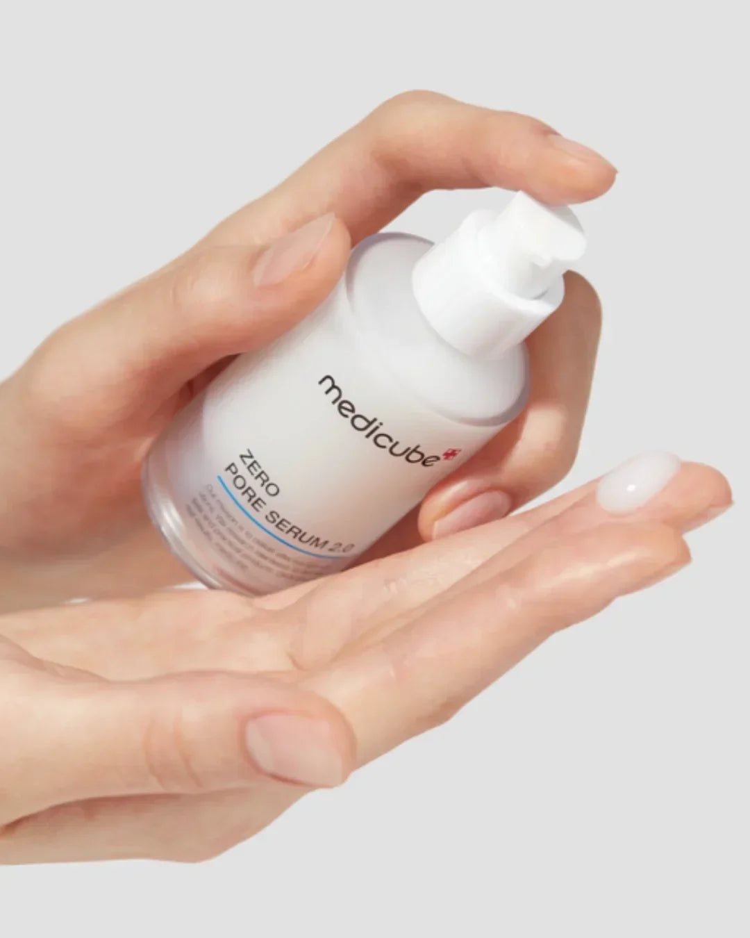 Hand dispensing Medicube Zero Pore Serum 2.0 with white serum drop on fingertip