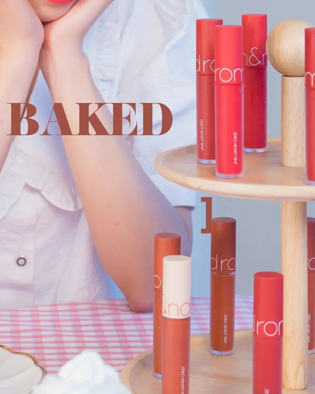 Display of red and brown lip tints on wooden stand with model in white blouse and baked text